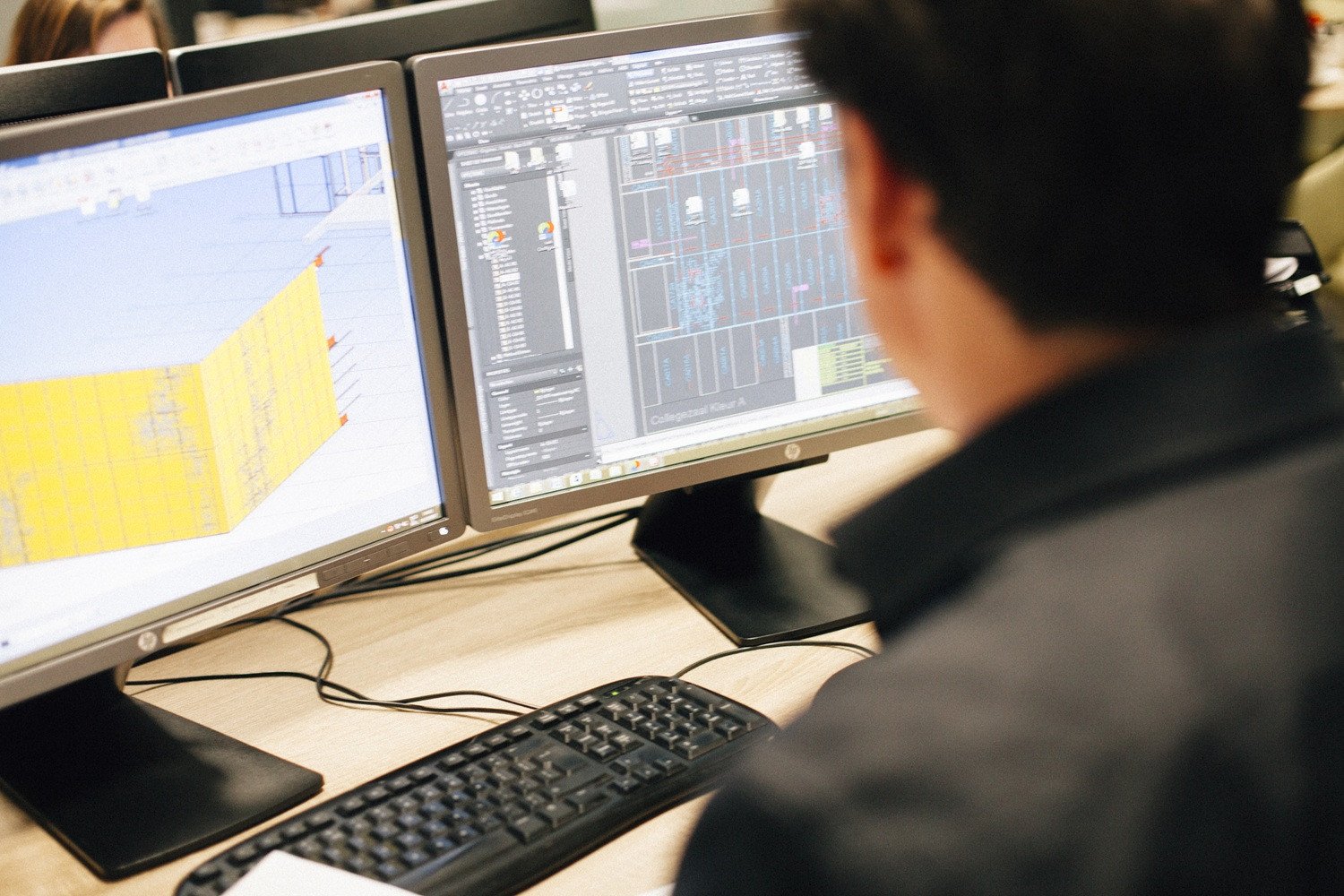 Engineer aan het werk bij VPT Versteeg, bezig met het ontwerpen van technische gevelonderdelen op twee computerschermen met 3D- en CAD-tekeningen.
